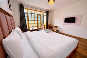 a large white bed in a room with a television at Hotel Naina Rockland , Manali in Vashisht +16 photos
