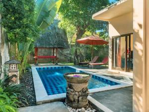 a swimming pool in a backyard with an umbrella at Terrace Bali Villa in Nusa Dua