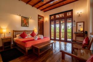 a bedroom with a bed with red pillows at Jim's Farm Villas in Madawala +57 photos