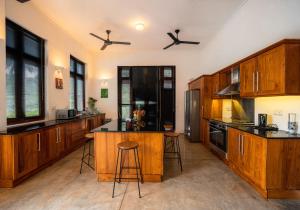 a large kitchen with wooden cabinets and a island at Jim's Farm Villas in Madawala