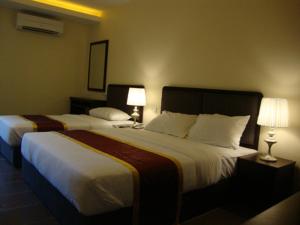 DM Hotel في كوتا كينابالو: سريرين في غرفة الفندق مع مصباحين