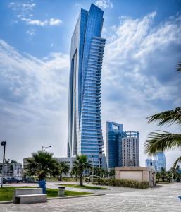 a tall skyscraper in a city with palm trees at Damac Al Jawharah Tower Versace Sea View شقة فرزاتشي بإطلالة بحرية برج داماك الجوهرة in Jeddah