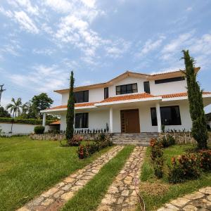 a large white house with a grass yard at Villa Conejo Miraflores in Chinauta
