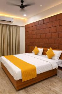 a bedroom with a large bed with yellow pillows at Anandi Hotel Guhagar in Guhagar