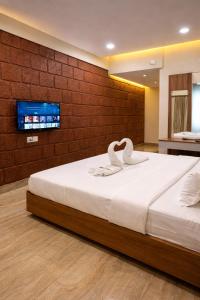 a bedroom with a bed with two swans on it at Anandi Hotel Guhagar in Guhagar
