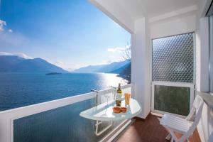 a balcony with a table and a view of the water at On the Lake 2BR with Garage in Porto Ronco - Happy Rentals in Ronco sopra Ascona +15 photos
