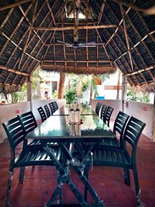 a dining table with chairs under a straw umbrella at Dreamy serenity beach side in Pondicherry