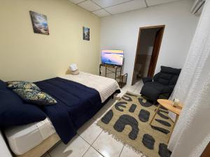 a bedroom with a bed and a couch and a television at BREEZE Hostal Boca Chica in Boca Chica