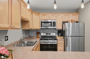 a kitchen with wooden cabinets and a stainless steel refrigerator at Alyeska Mountain Side Retreat! in Girdwood