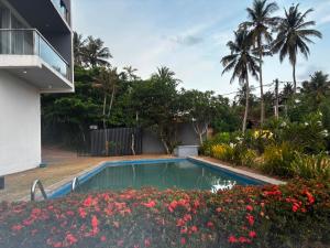 a swimming pool in the yard of a house with flowers at Mazarin Hiriketiya in Dickwella
