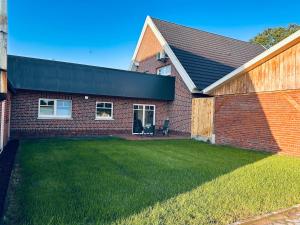 a brick house with a lawn in front of it at Ferienwohnung am Vechtedamm in Hoogstede