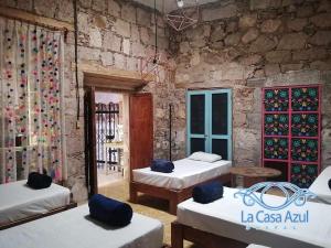 a room with three beds and a stone wall at La Casa Azul Hostal in Morelia