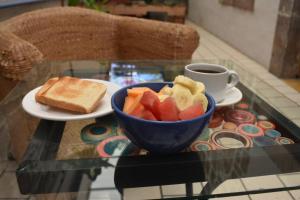 a bowl of fruit and toast on a table with a cup of coffee at La Casa Azul Hostal in Morelia