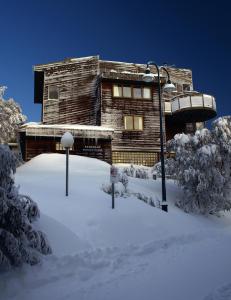 una casa de madera en la nieve con árboles nevados en Ski Club of Victoria - Kandahar Lodge en Mount Buller
