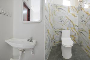 a bathroom with a sink and a toilet and a mirror at Super Hotel O Gandimaisamma Thalli Temple Formerly GN Luxury Suits in Dhundgol