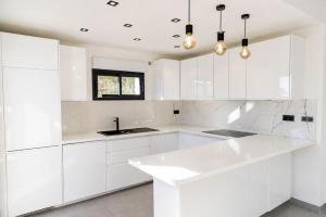 a white kitchen with white cabinets and a sink at Villa 6 pers à 30m de la mer in Sainte-Maxime