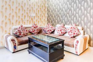 a living room with a couch with pillows and a table at Super Hotel O Gomti Nagar Vigyan khand in Lucknow