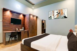a bedroom with a bed and a desk and a television at Super Hotel O Gomti Nagar Vigyan khand in Lucknow +27 photos