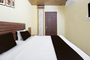 a bedroom with a white bed and a brown door at Hotel O Uttaranchal University Dehradun in Jhājra