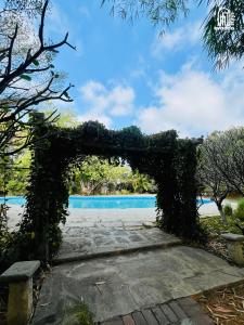 an arch covered in ivy in front of a pool at The Hideaway Hosur by evaddo stays in Hosūr