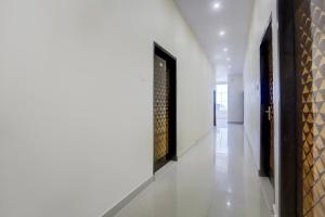 a hallway with white walls and a black door at OYO Collection O Kalyanpur Metro Station in Kaliānpur