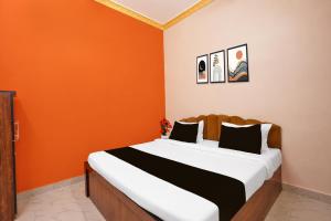 a bedroom with a bed with an orange wall at Hotel O AIIMS Raipur in Raipur
