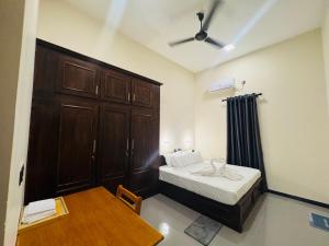 a small bedroom with a bed and a wooden cabinet at nama villa in Arugam Bay