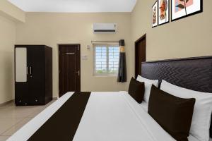 a bedroom with a large bed with black and white pillows at Super Hotel O Temple Road Vemulavada in Karīmnagar