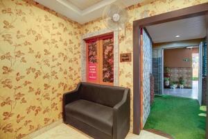 a living room with a chair and a fan at Collection O Downtown Hospital Guwahati Formerly Cherry City Cottage in Guwahati