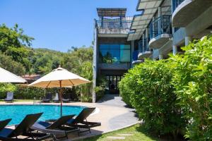 a pool with chairs and an umbrella next to a building at Seaflower Bungalows in Srithanu