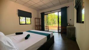 a bedroom with a bed and a large window at Elevara Eco Resort - Wasgamuwa in Kathurupitiya