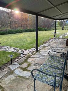 a stone patio with a bench under a pavilion at Coppabella Cottage in Jingellic