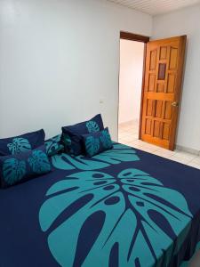 a bedroom with a bed with a blue comforter at Fare Havai - Raiatea in Taputapuapea