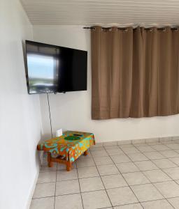 a tv hanging on a wall with a table in a room at Fare Havai - Raiatea in Taputapuapea