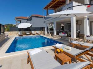 a swimming pool with chairs and a house at Vacation home Marin in Vinišće