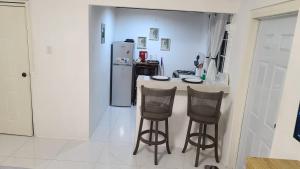 a kitchen with two bar stools and a refrigerator at Lorenton Hideaway Studio in Lucea