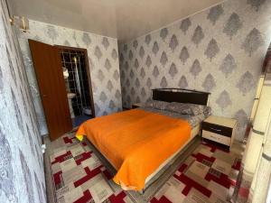ein Schlafzimmer mit einem Bett mit einer orangefarbenen Decke in der Unterkunft Baisuu in Bosteri