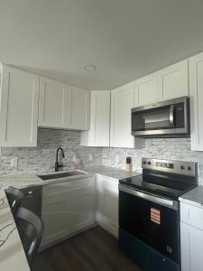 a kitchen with white cabinets and a stove and a microwave at Only minutes away from Surfside Beach in Freeport