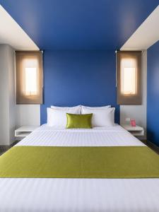 a blue bedroom with a white bed with a green pillow at iCheck inn Phuket Town in Phuket
