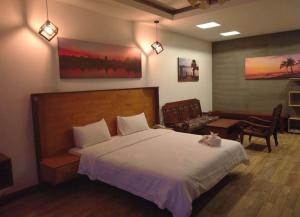 a bedroom with a large bed and a living room at KN Guesthosue in Phumĭ Réach Born (1)
