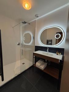 a bathroom with a shower and a sink and a mirror at Flore Hôtel & Jardin The Originals Relais in Vichy +33 photos
