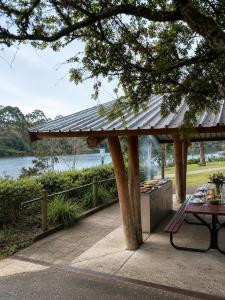 a pavilion with a table and a bench next to a lake at Garden Studio with Private Patio in Wentworth Falls