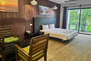 a bedroom with a bed and a chair and a window at KN Guesthosue in Phumĭ Réach Born (1)