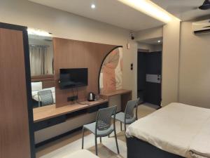 a bedroom with a bed and a desk with a television at Hotel Radhika in Lātūr