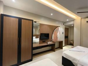a bedroom with a bed and a desk with a television at Hotel Radhika in Lātūr