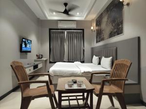 a hotel room with a bed and two chairs and a table at Hotel Radhika in Lātūr