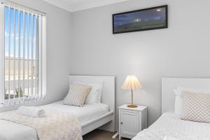 a white room with two beds and a window at Alkimos Coastal Escape in Alkimos