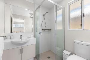 a white bathroom with a shower and a sink at Alkimos Coastal Escape in Alkimos +9 photos
