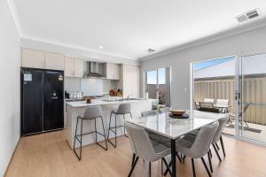 a kitchen and dining room with a table and chairs at Alkimos Coastal Escape in Alkimos