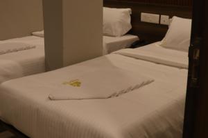 two beds in a hotel room with white sheets at Grand Heritage in Ernakulam +21 photos